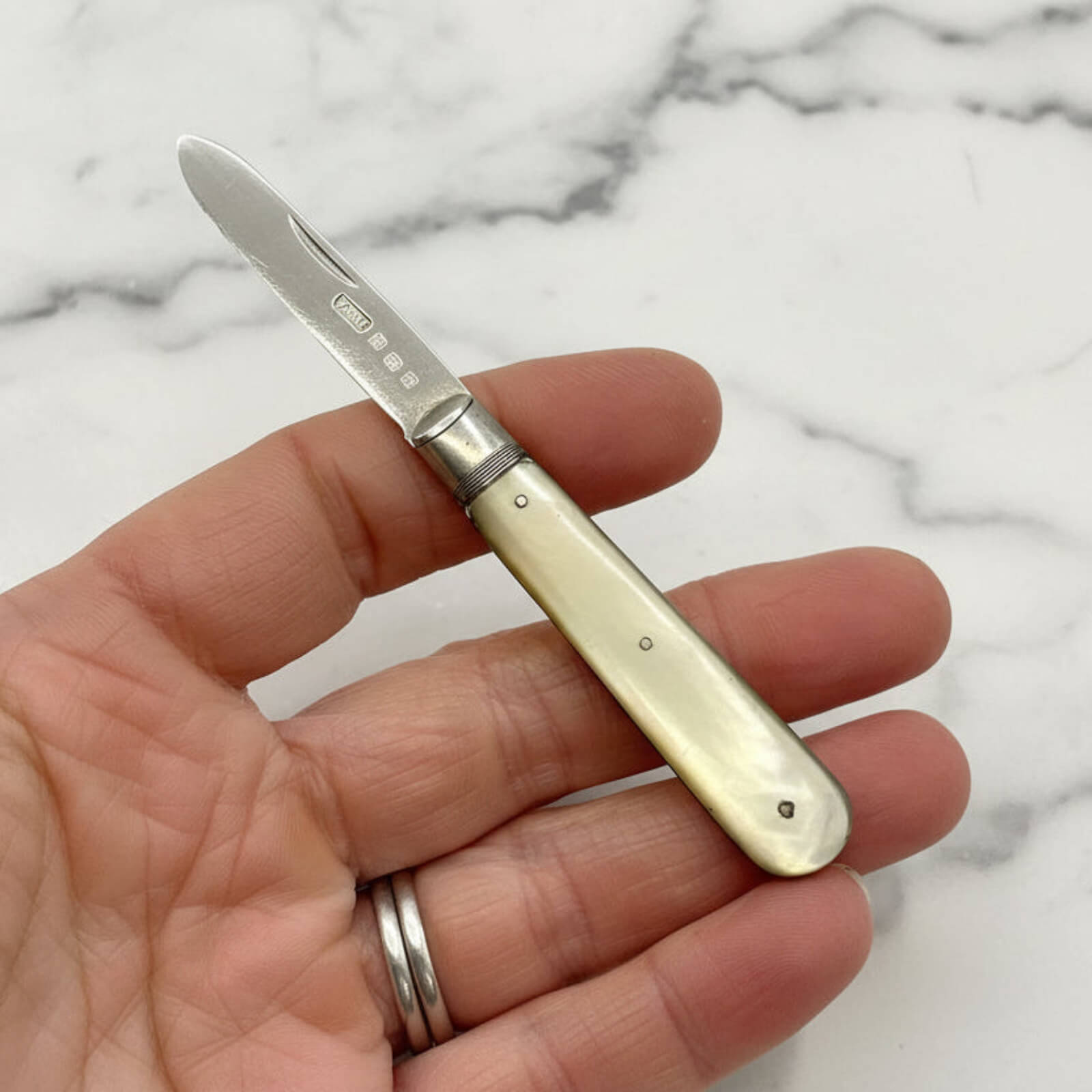 Small pocket knife held in a hand against a marble background