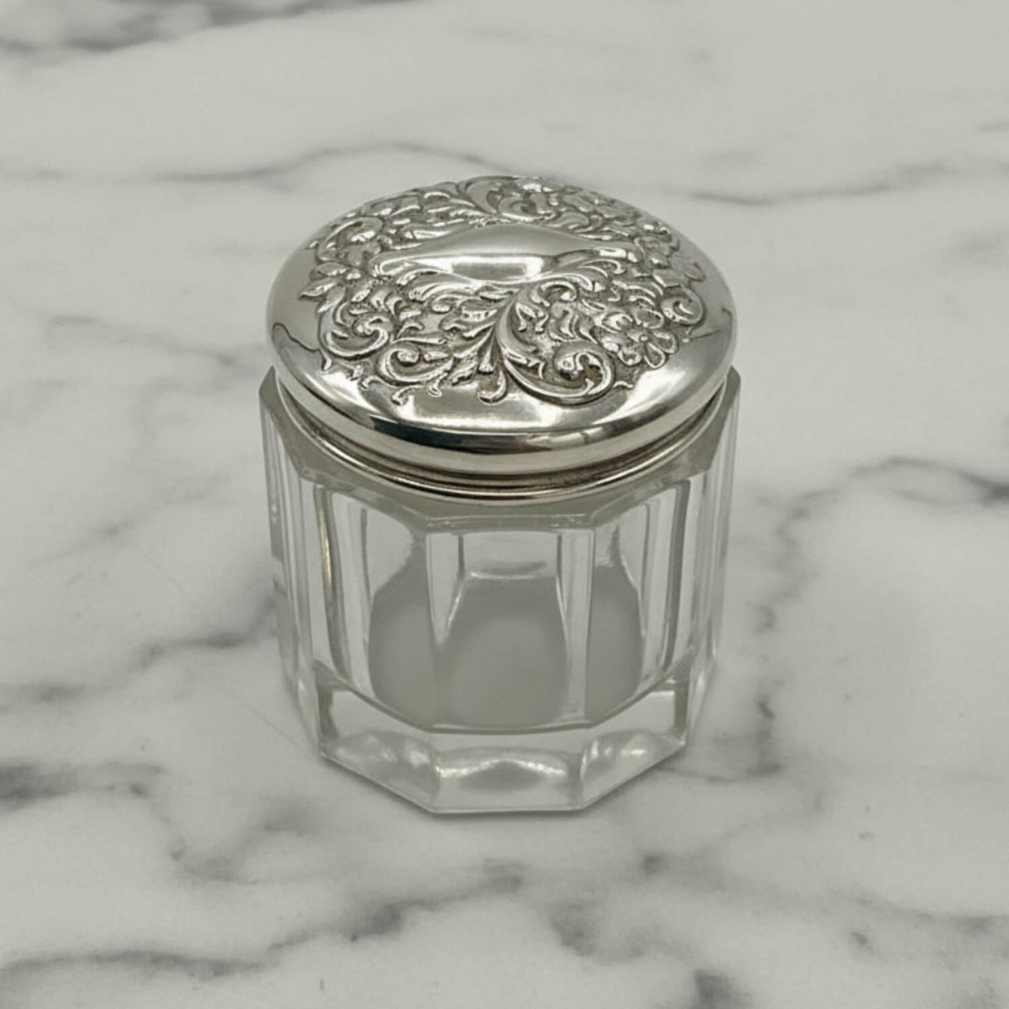 Clear glass jar with a silver lid on a marble surface
