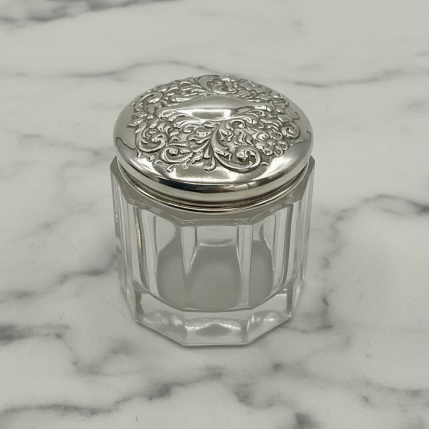 Clear glass jar with a silver lid on a marble surface