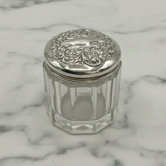 Clear glass jar with a silver lid on a marble surface