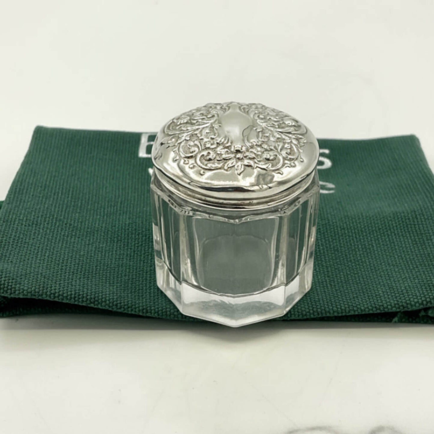 Clear glass jar with silver lid on a green cloth bag