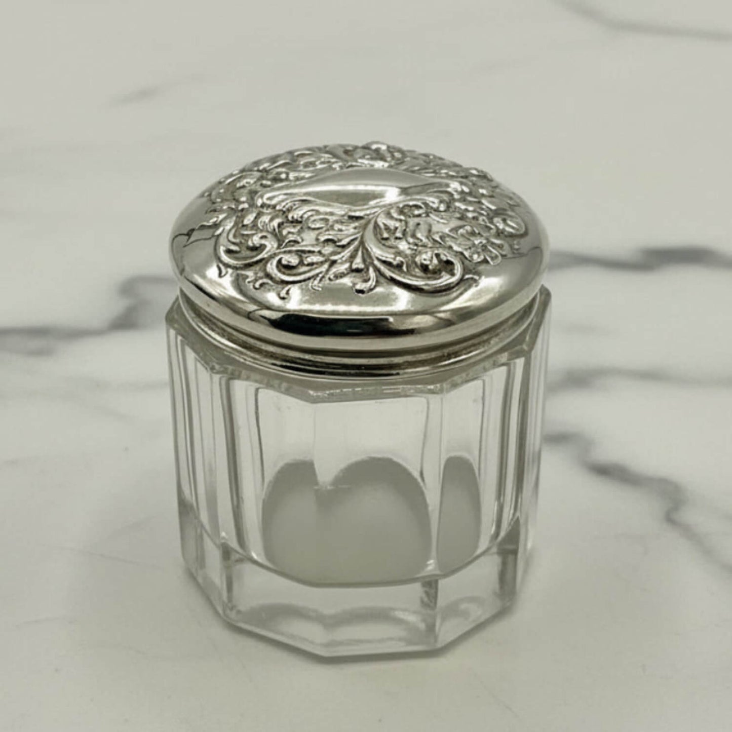 Clear glass jar with a silver lid on a marble surface