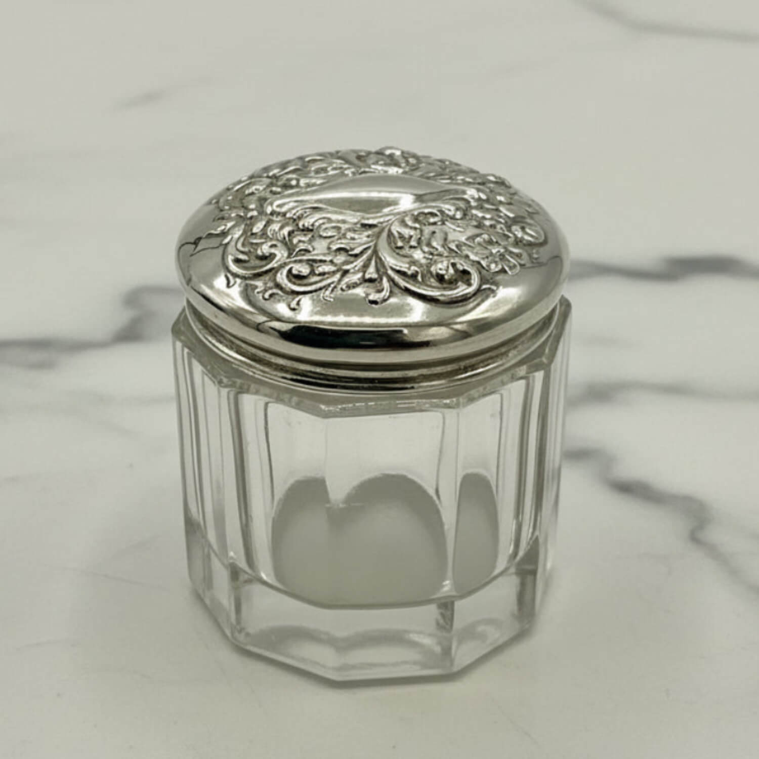 Clear glass jar with a silver lid on a marble surface
