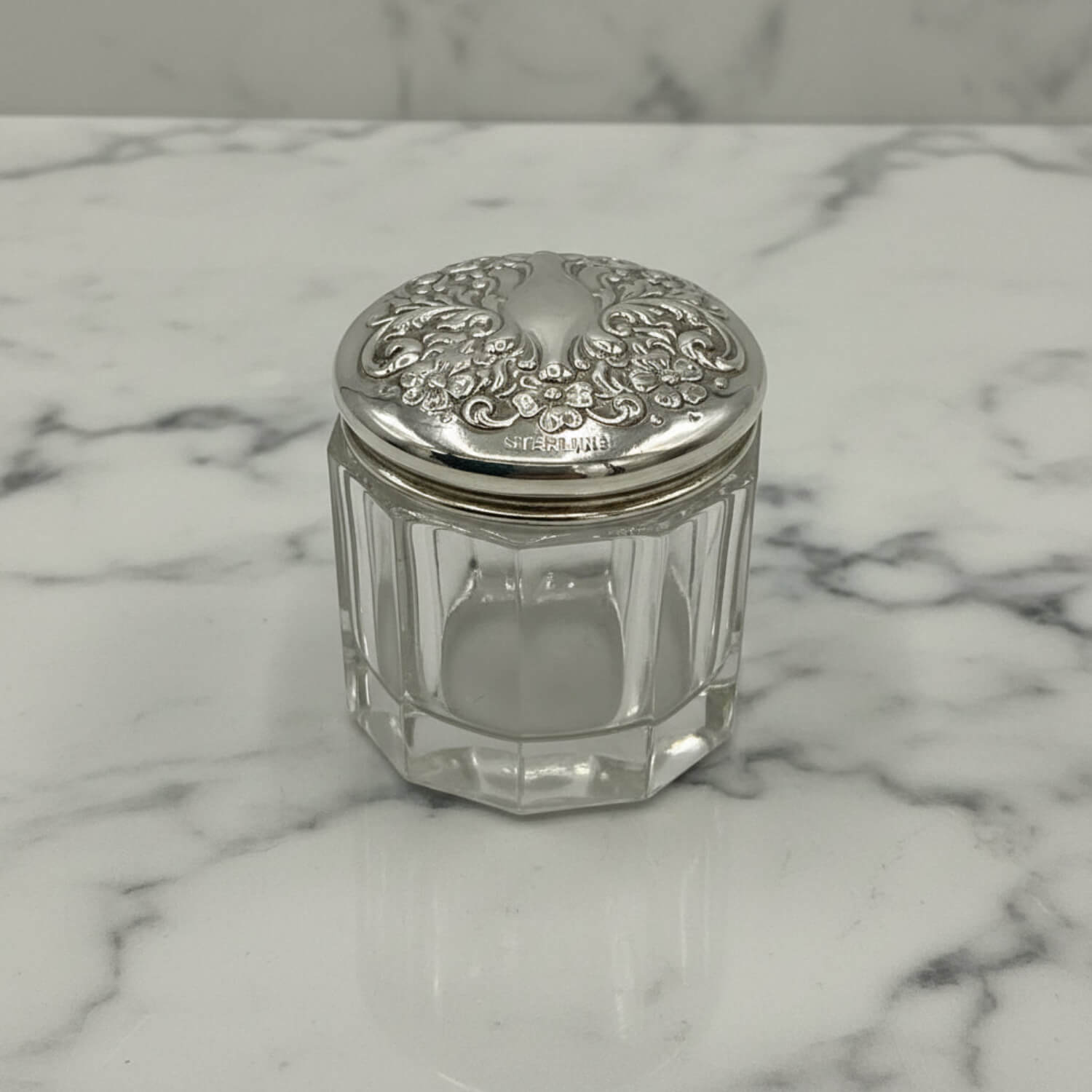 Clear glass jar with silver lid on a marble surface
