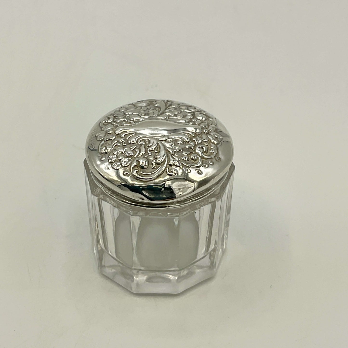 Small glass jar with a silver lid on a white background