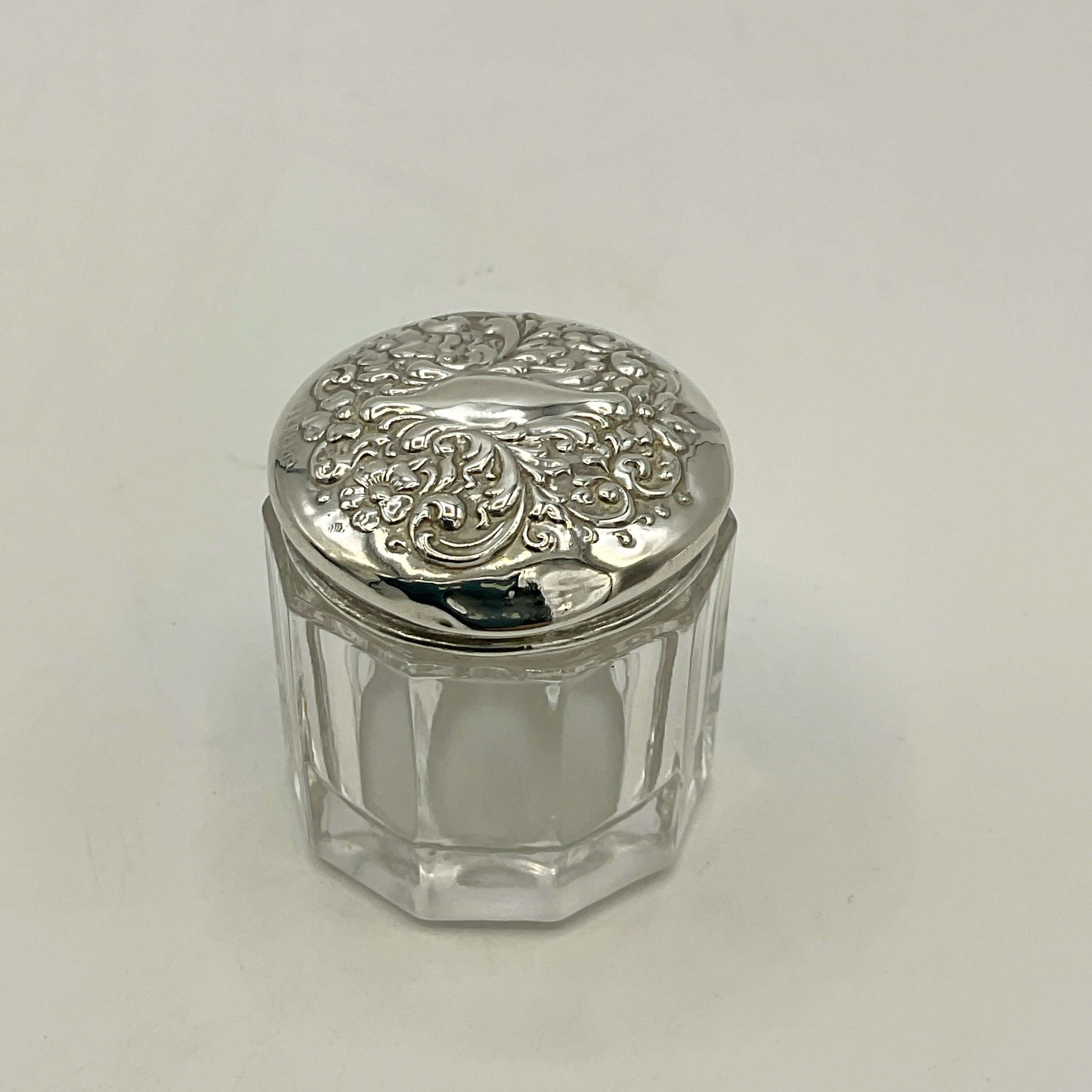 Small glass jar with a silver lid on a white background