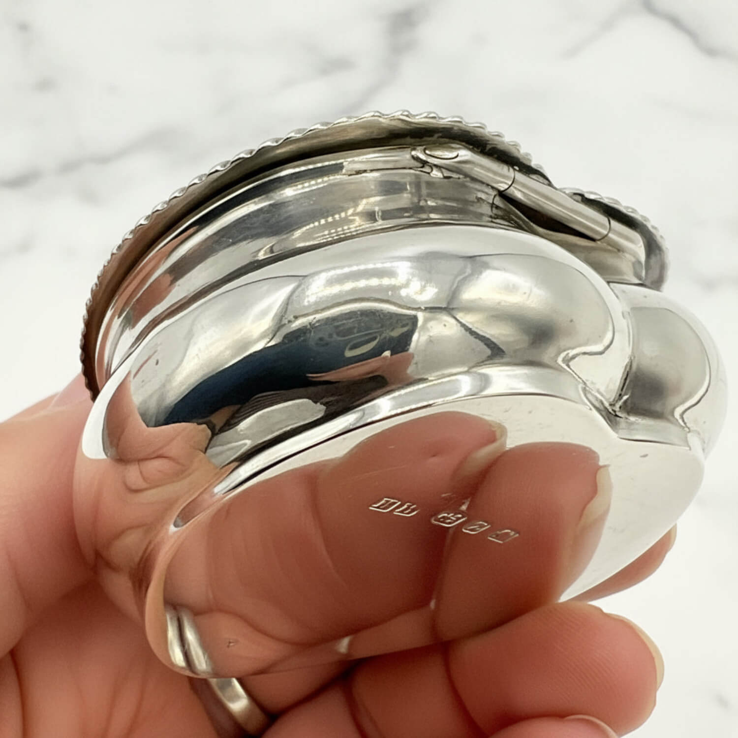 Close-up of a silver box held in a hand with a blurred background