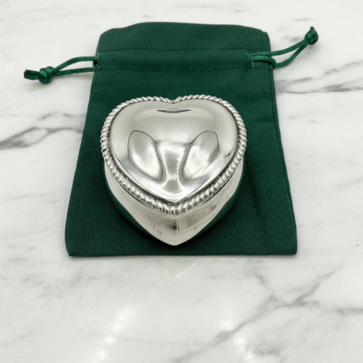 Antique Sterling Silver Heart Shaped Jewellery Box on a green bag and marble worktop