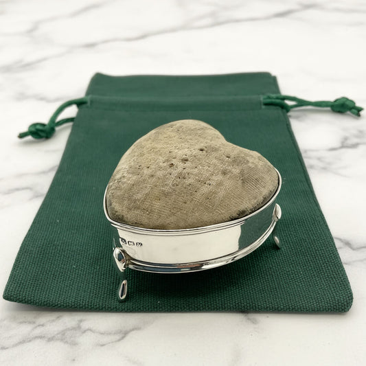 Heart-shaped pincushion with silver base on a green drawstring bag