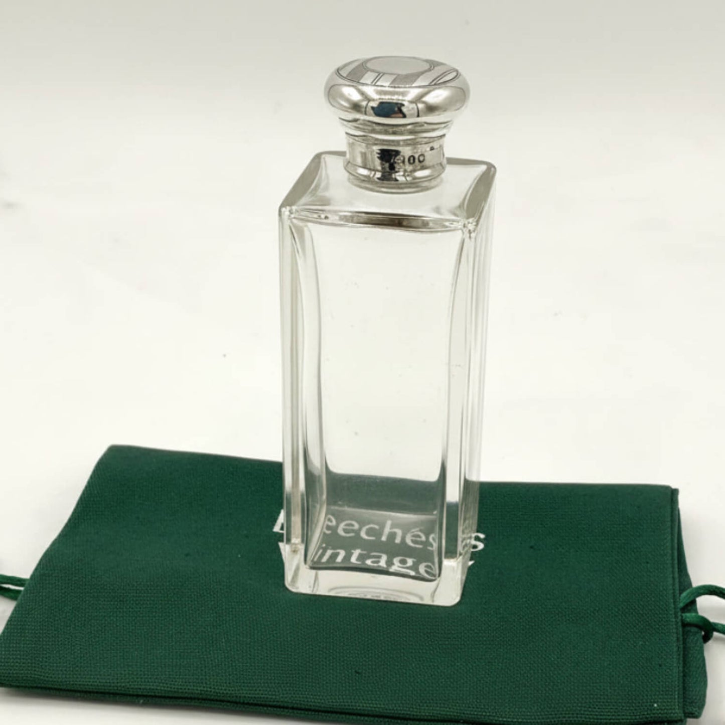 Antique Sterling Silver Topped Bottle on a green bag with a clear background