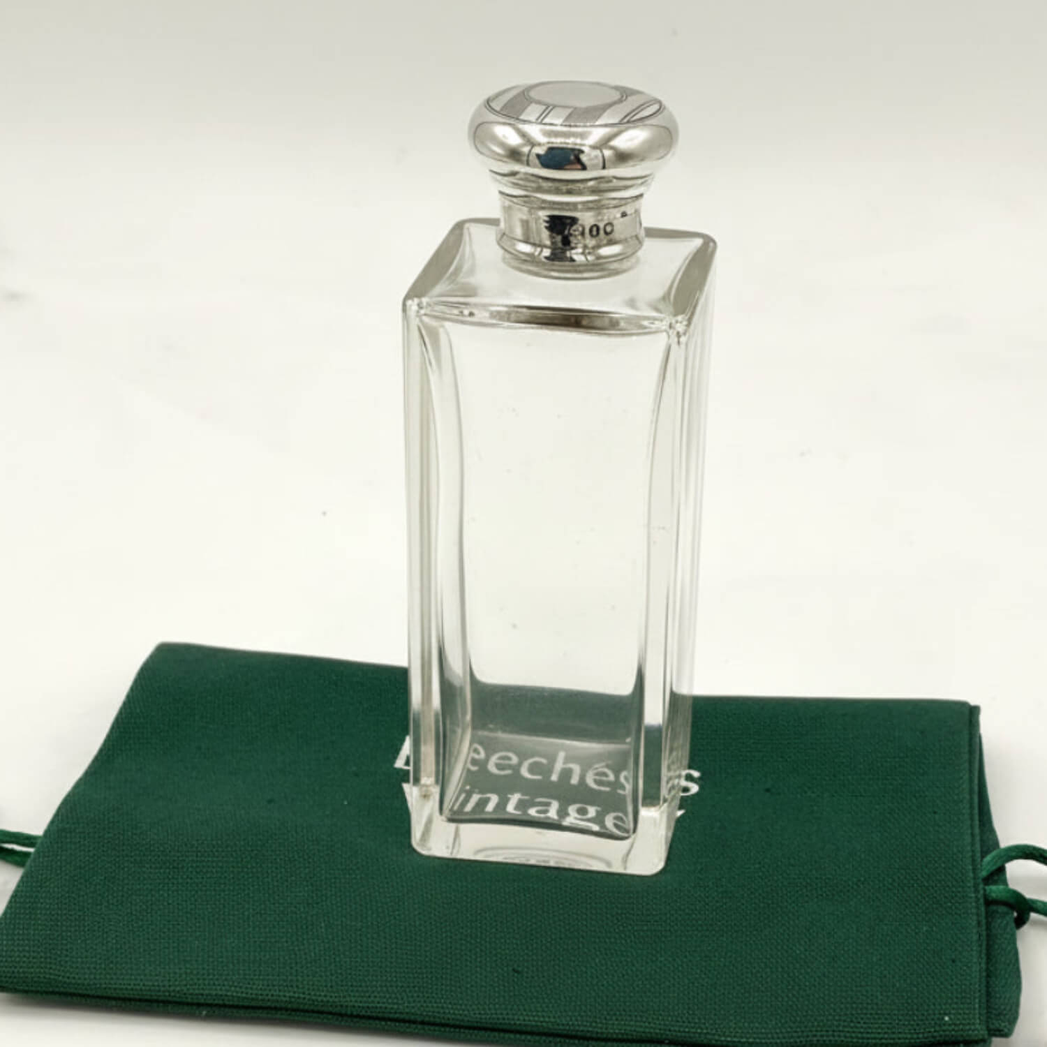 Antique Sterling Silver Topped Bottle on a green bag with a clear background