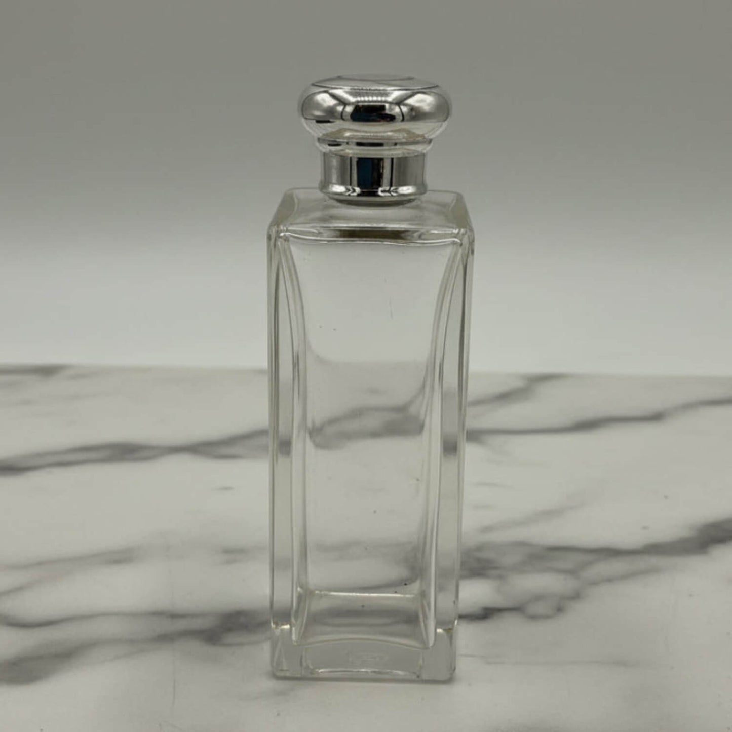 Clear glass bottle with silver cap on a marble surface