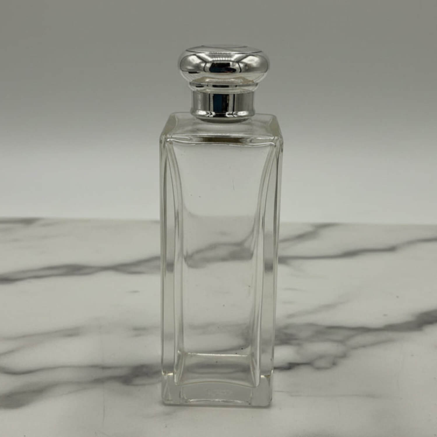 Clear glass bottle with silver cap on a marble surface