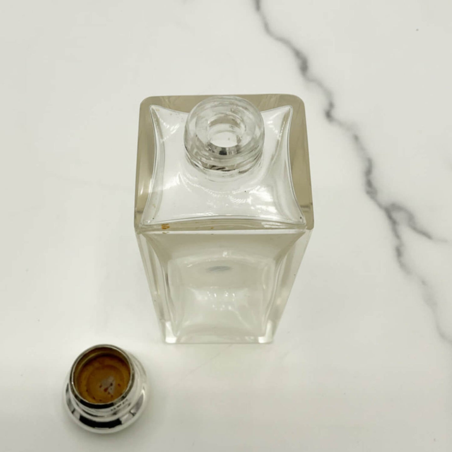 Antique Sterling Silver Topped Bottle with the lid off on a marble surface