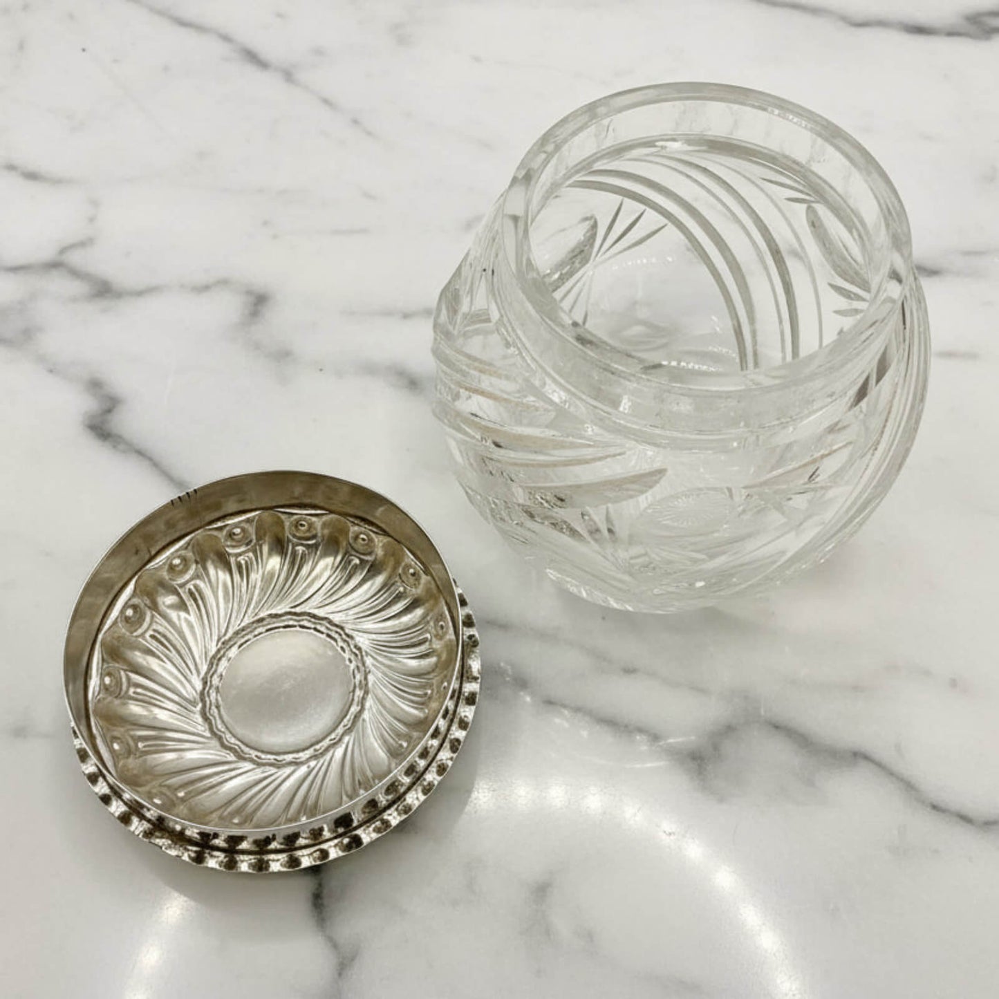 Decorative glass jar with silver lid on a marble surface