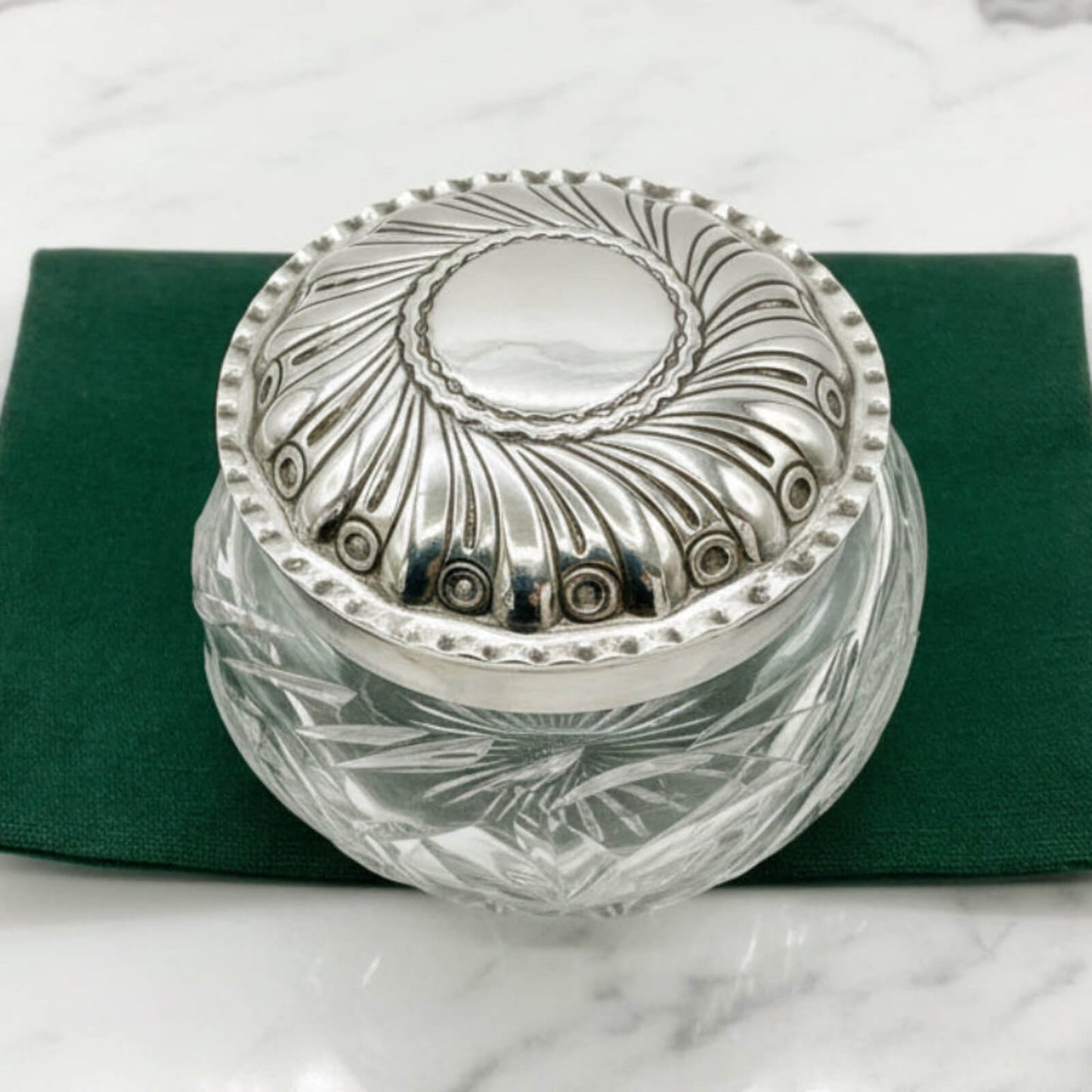 Decorative glass jar with silver lid on a green bag