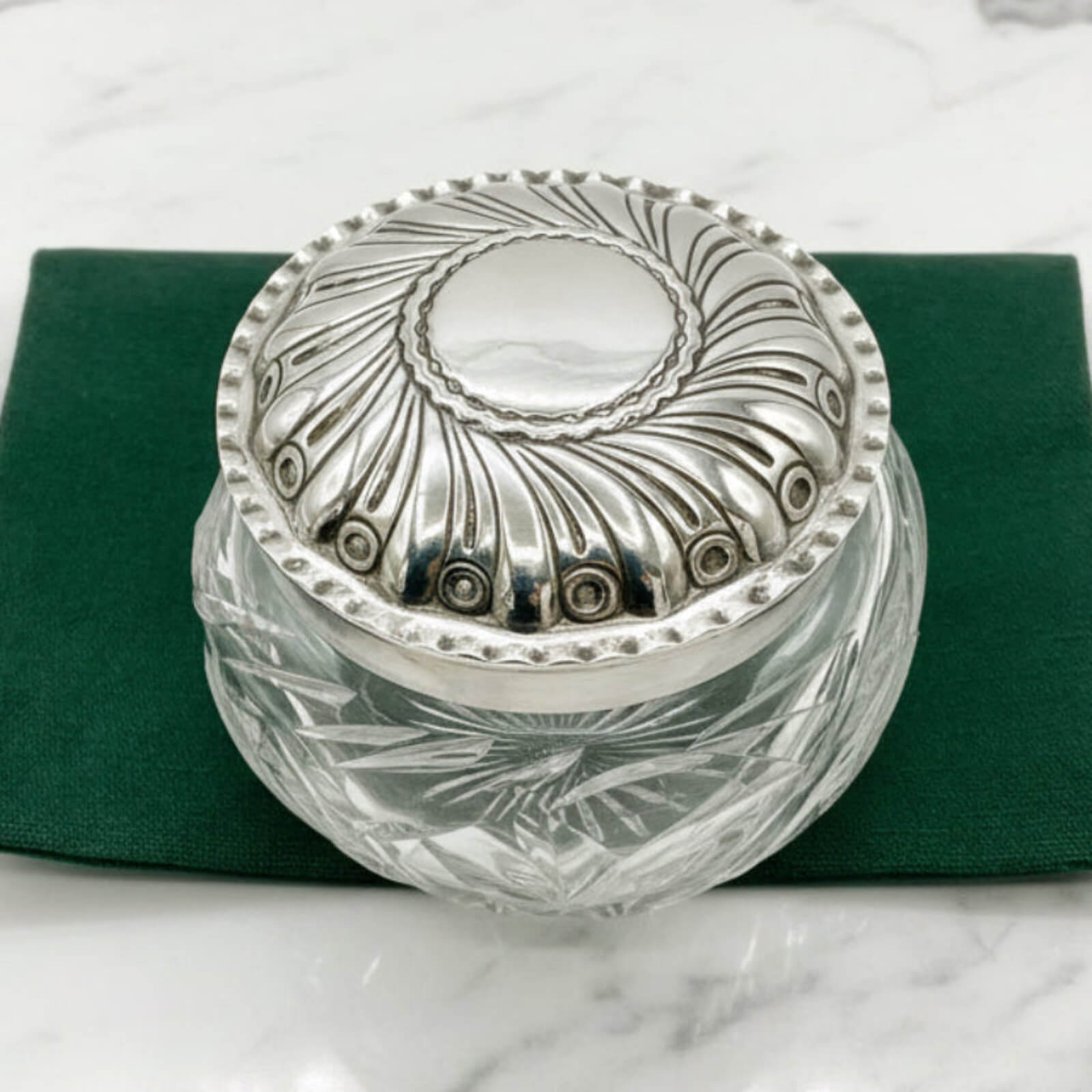 Decorative glass jar with silver lid on a green bag