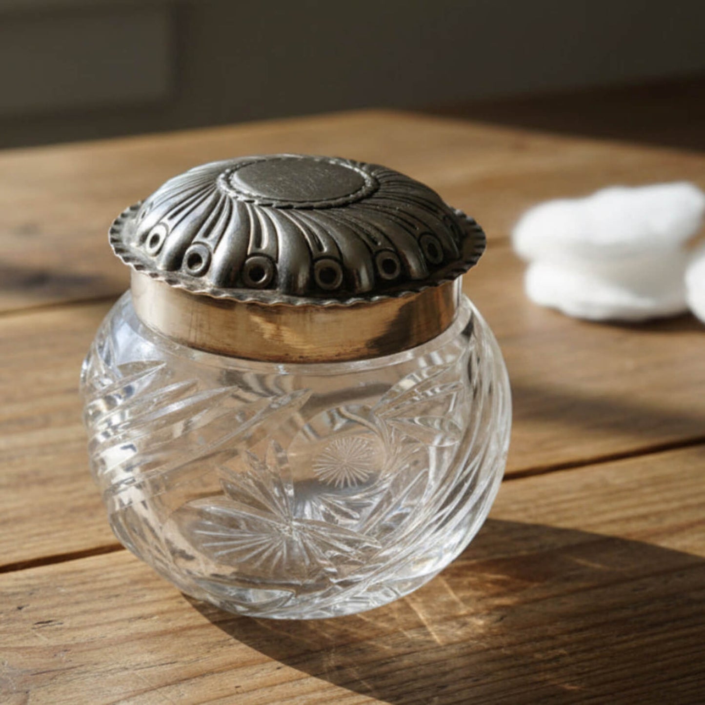 Clear glass jar with decorative silver lid on a wooden surface