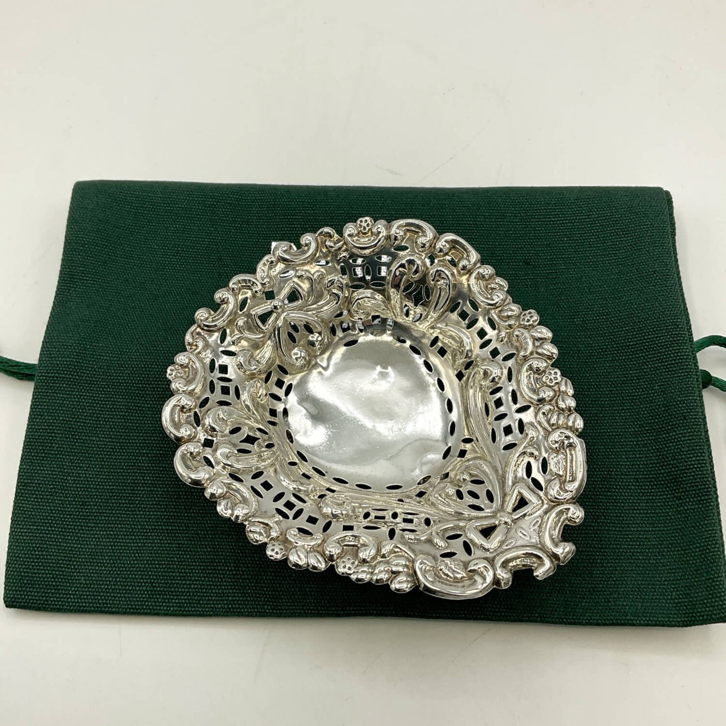 Silver decorative item on a green fabric background