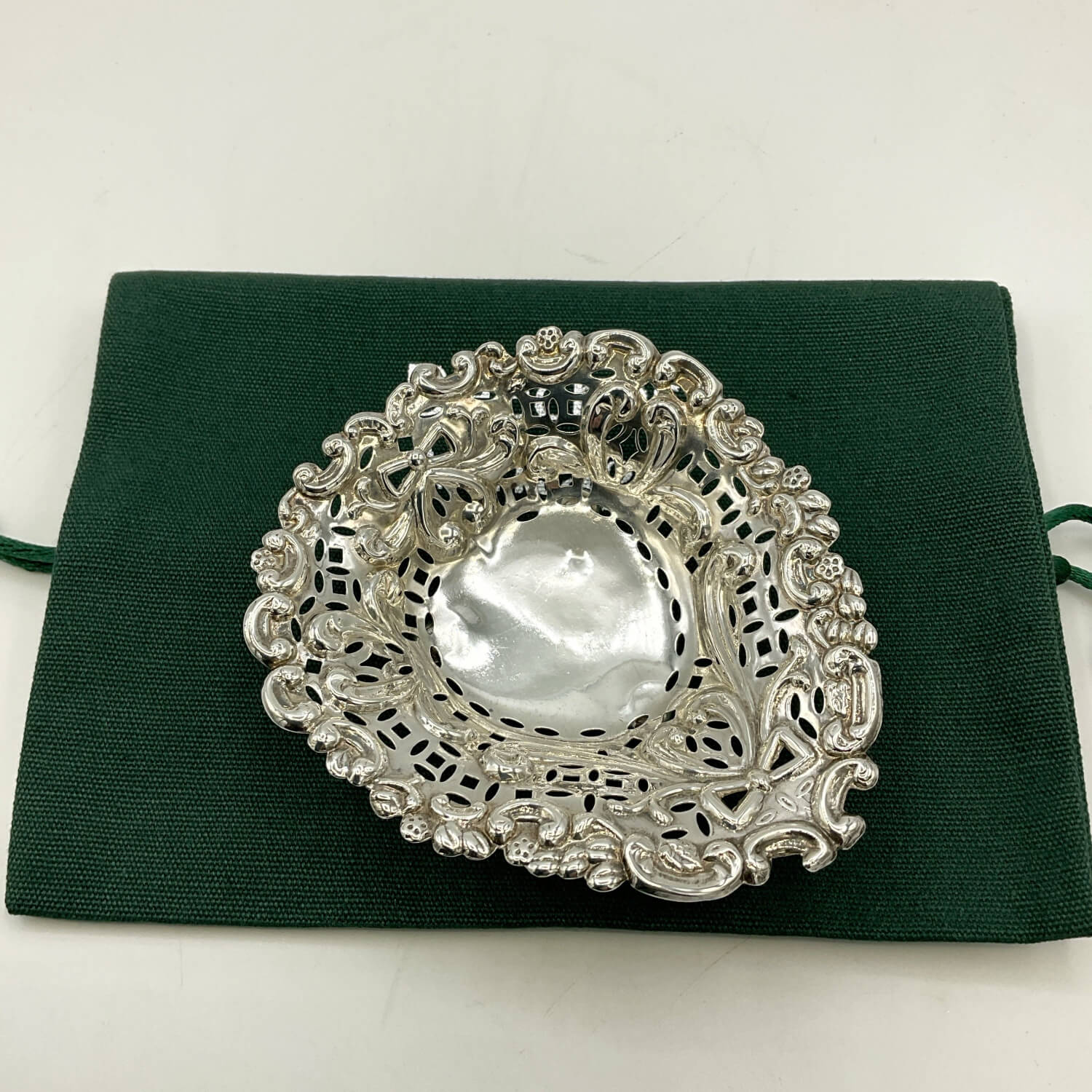 Silver decorative item on a green fabric background