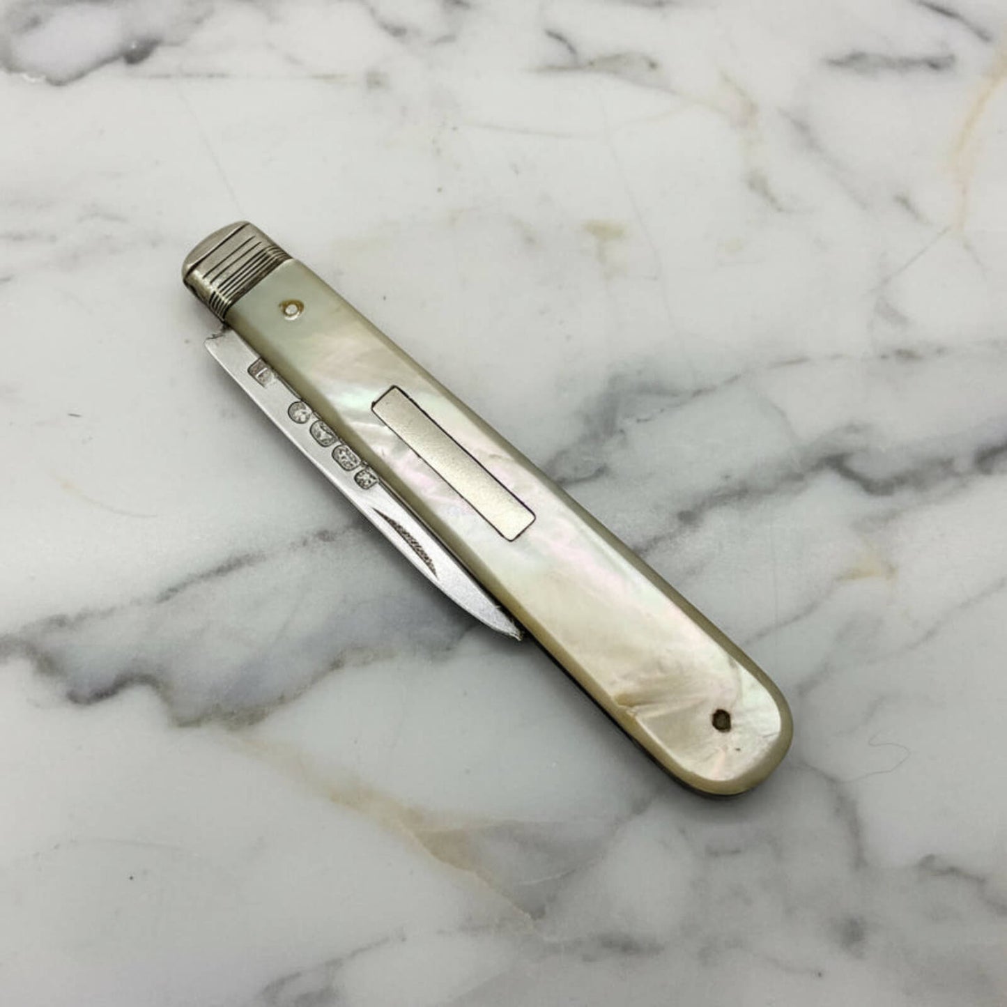 Vintage pocket knife with a decorative handle on a marble surface