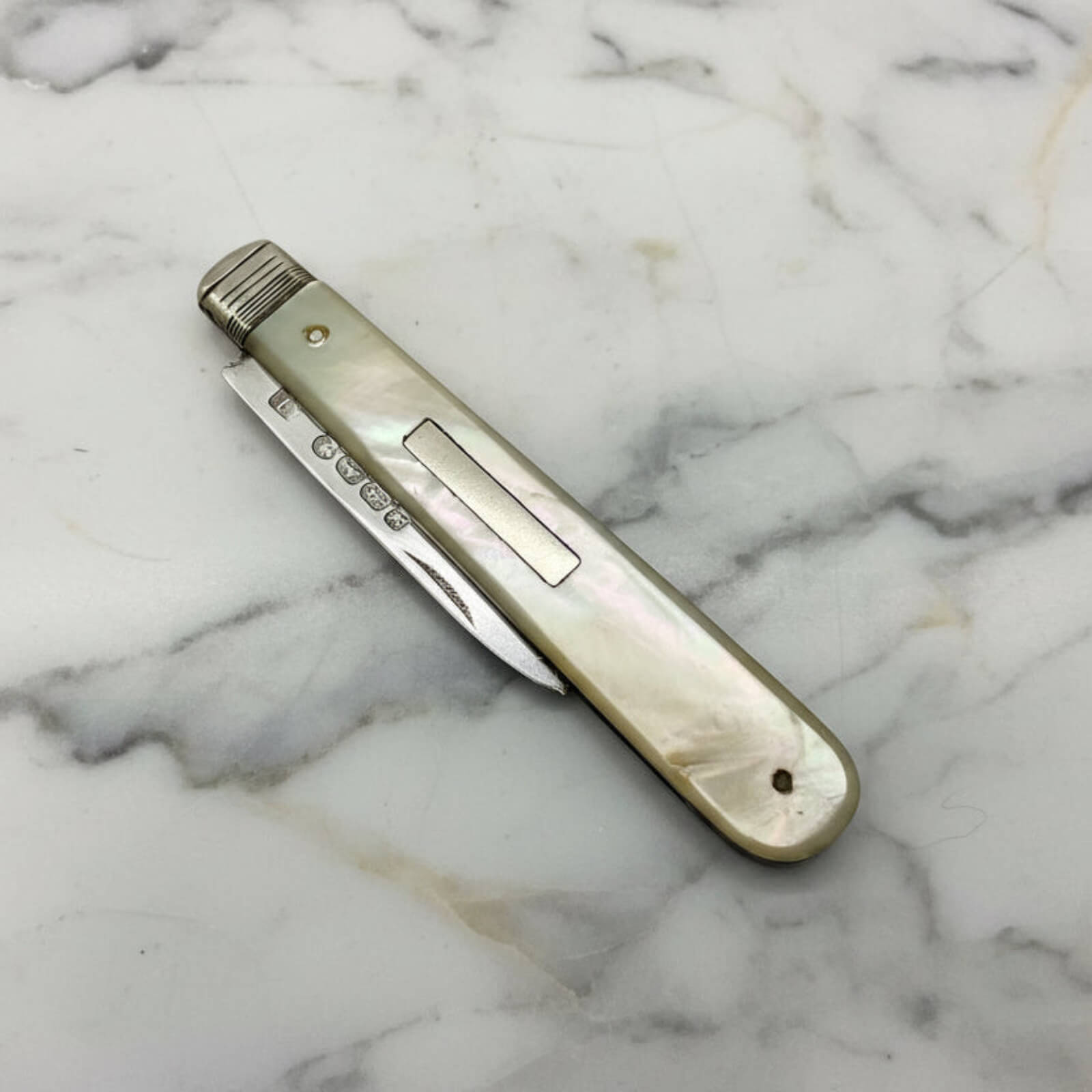 Vintage pocket knife with a decorative handle on a marble surface