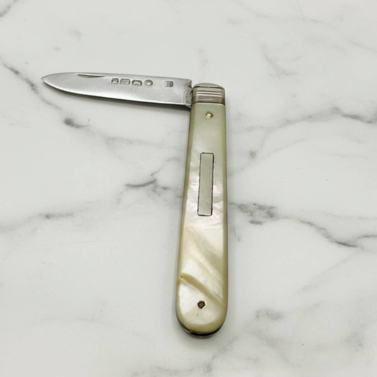 Pocket knife with a decorative handle on a marble surface