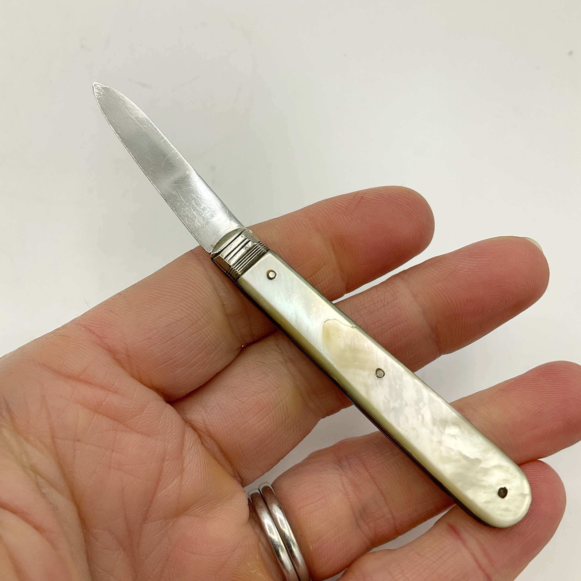 Hand holding a small pocket knife with a decorative handle on a white background