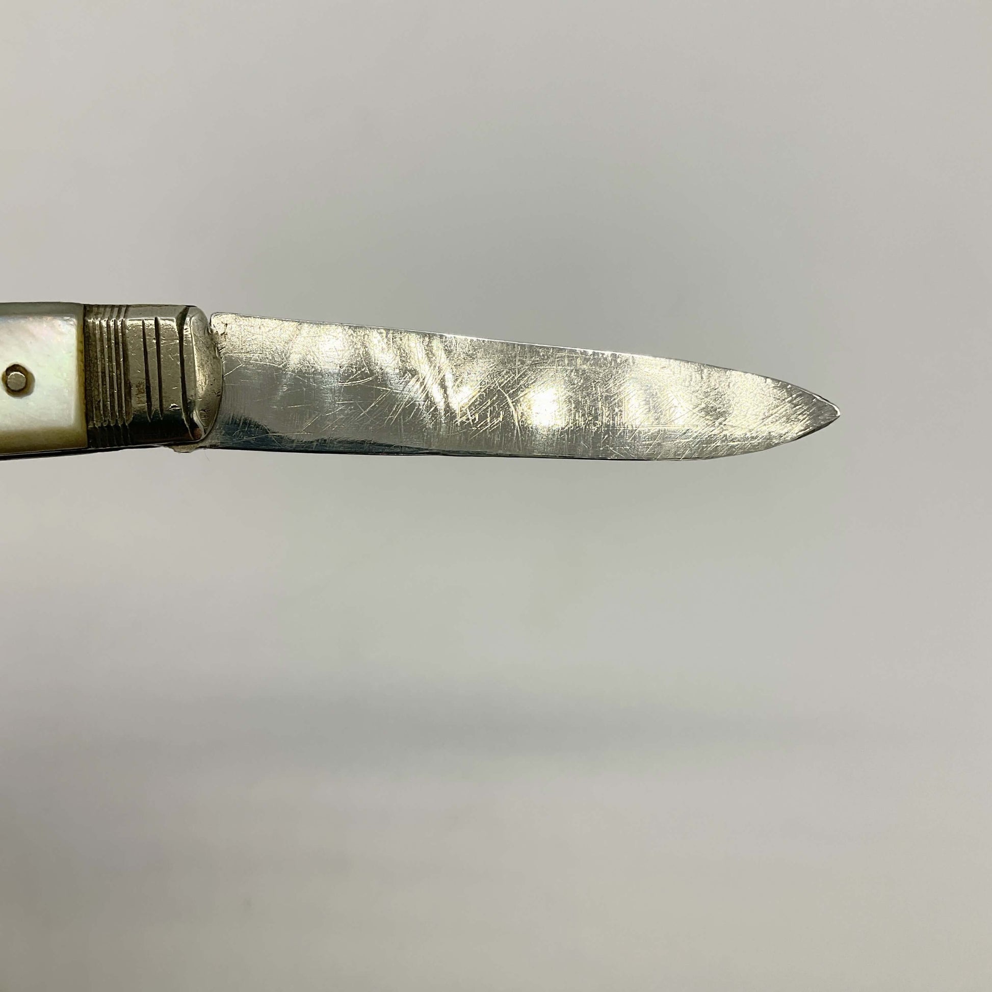 Close-up of a pocket knife blade on a gray background