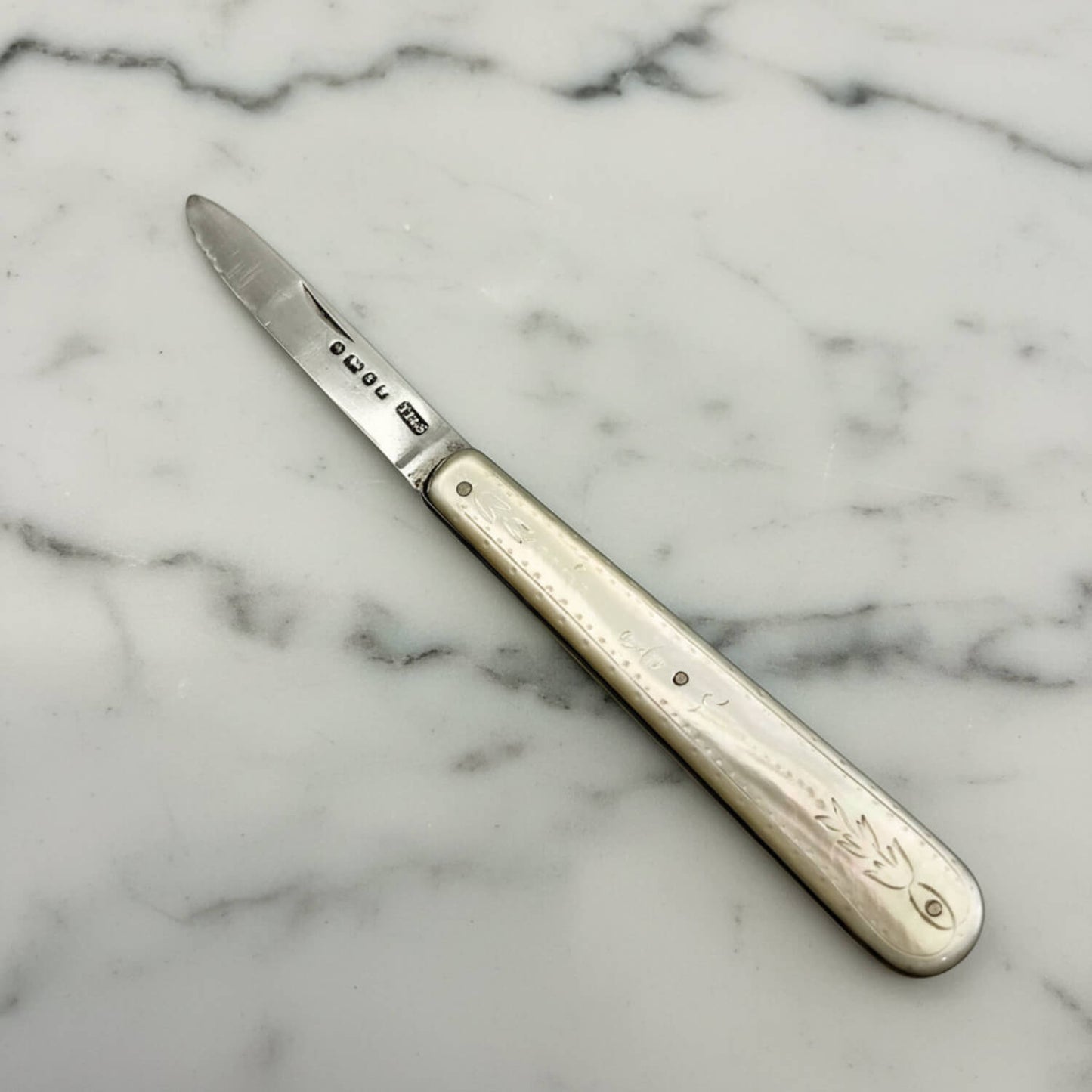 Silver knife with a decorative handle on a marble surface