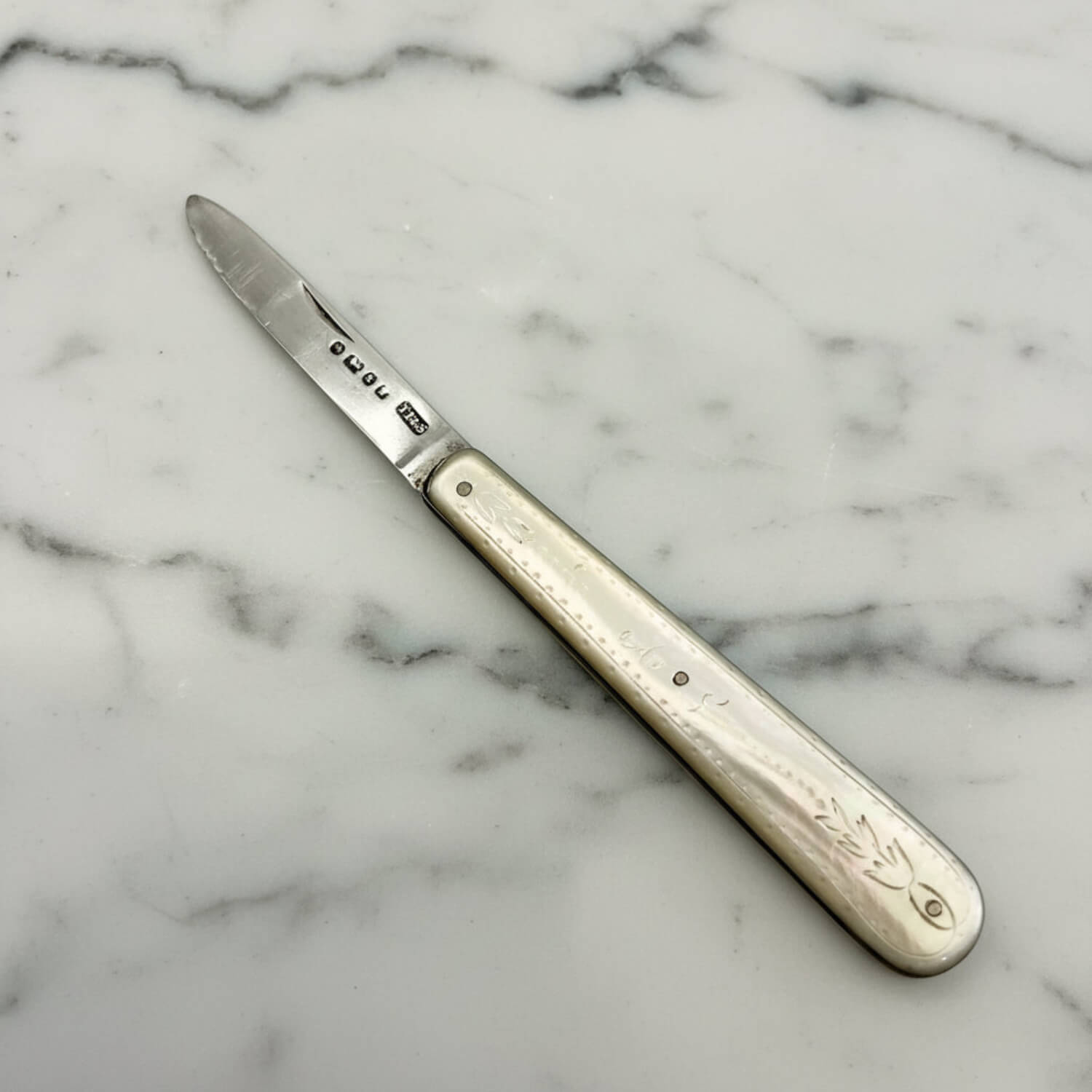 Silver knife with a decorative handle on a marble surface