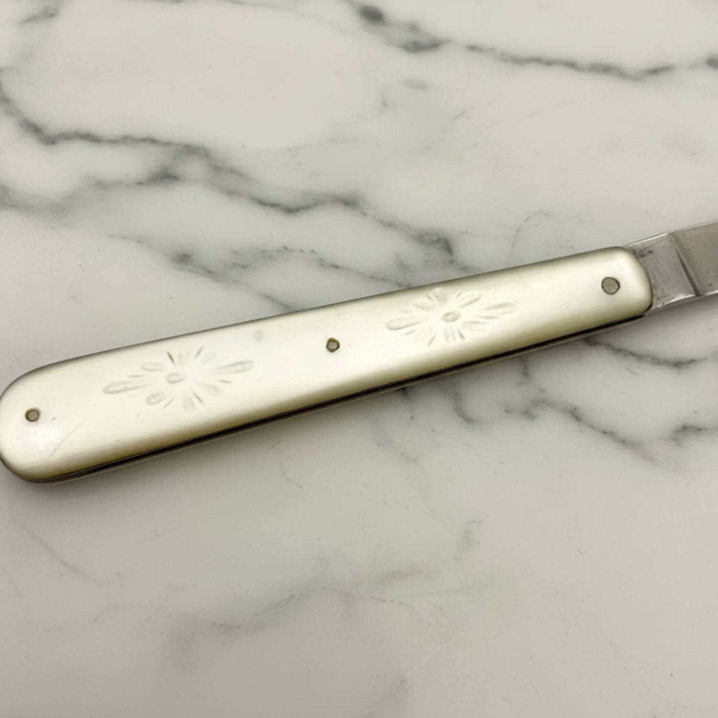 Fruit knife with decorative pearl  handle on a marble surface