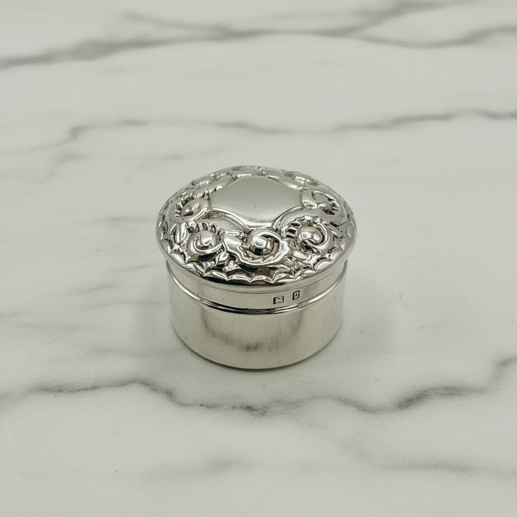 Silver decorative box with intricate designs on a marble surface