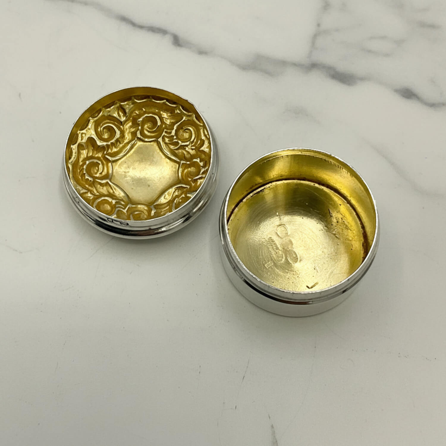 Gold and silver round pill box on a marble surface