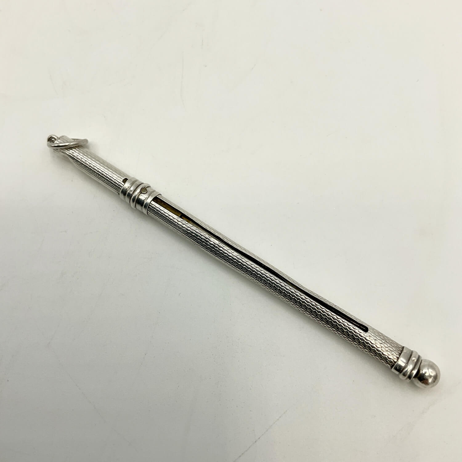 A Art Deco Sterling Silver Cocktail Whisk with a textured grip and a small loop at one end, photographed on a plain light background.
