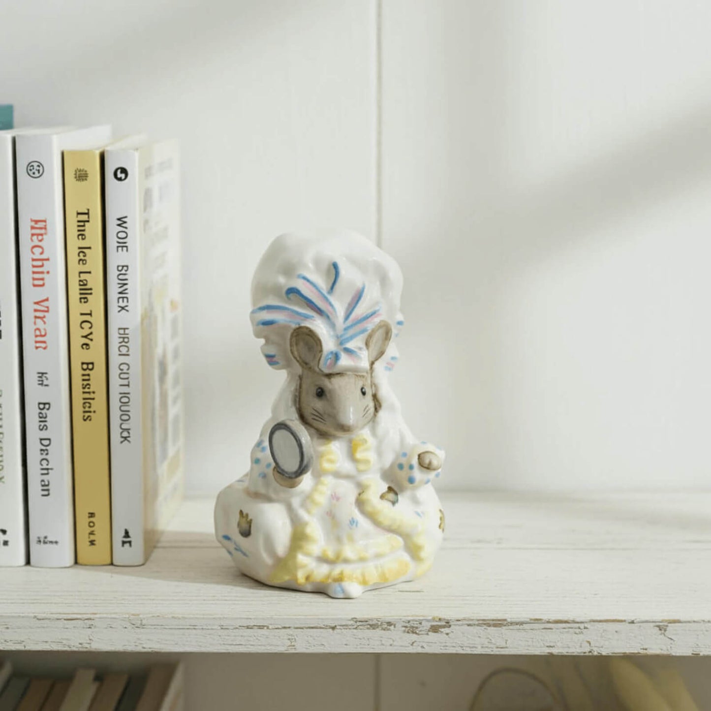 Decorative figurine of a mouse with a headdress on a shelf with books