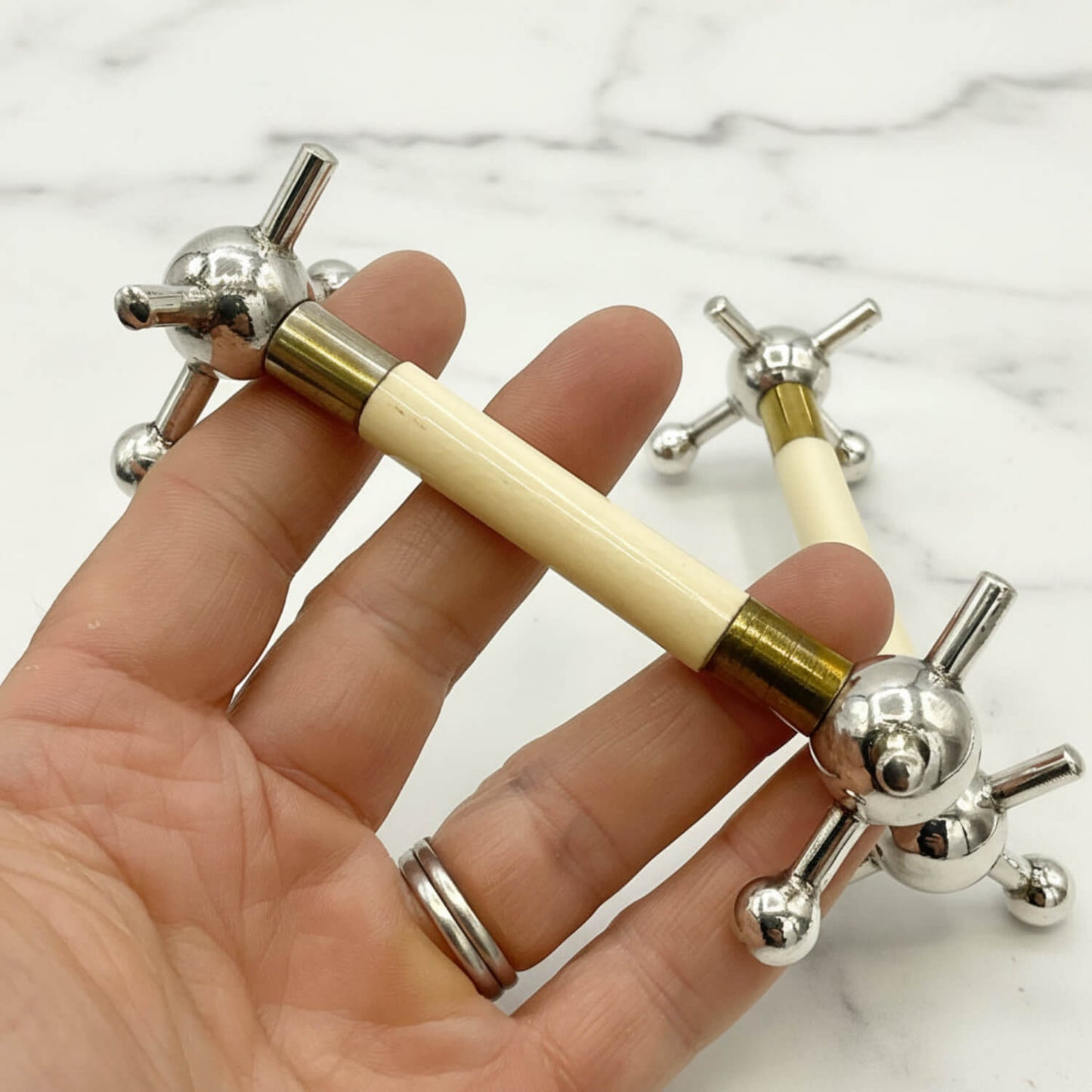 Pair of Antique Silver Plated Knife Rests held in hand with marble surface