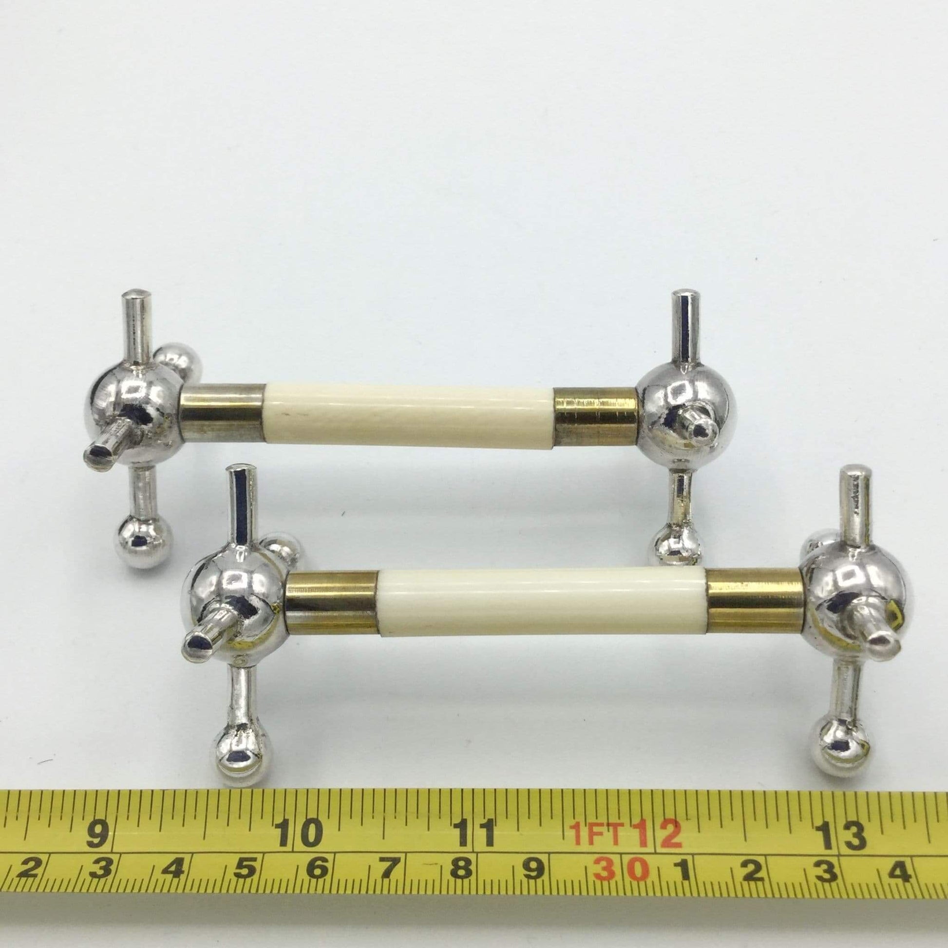 Pair of Antique Silver Plated Knife Rests next to a tape measure for scale