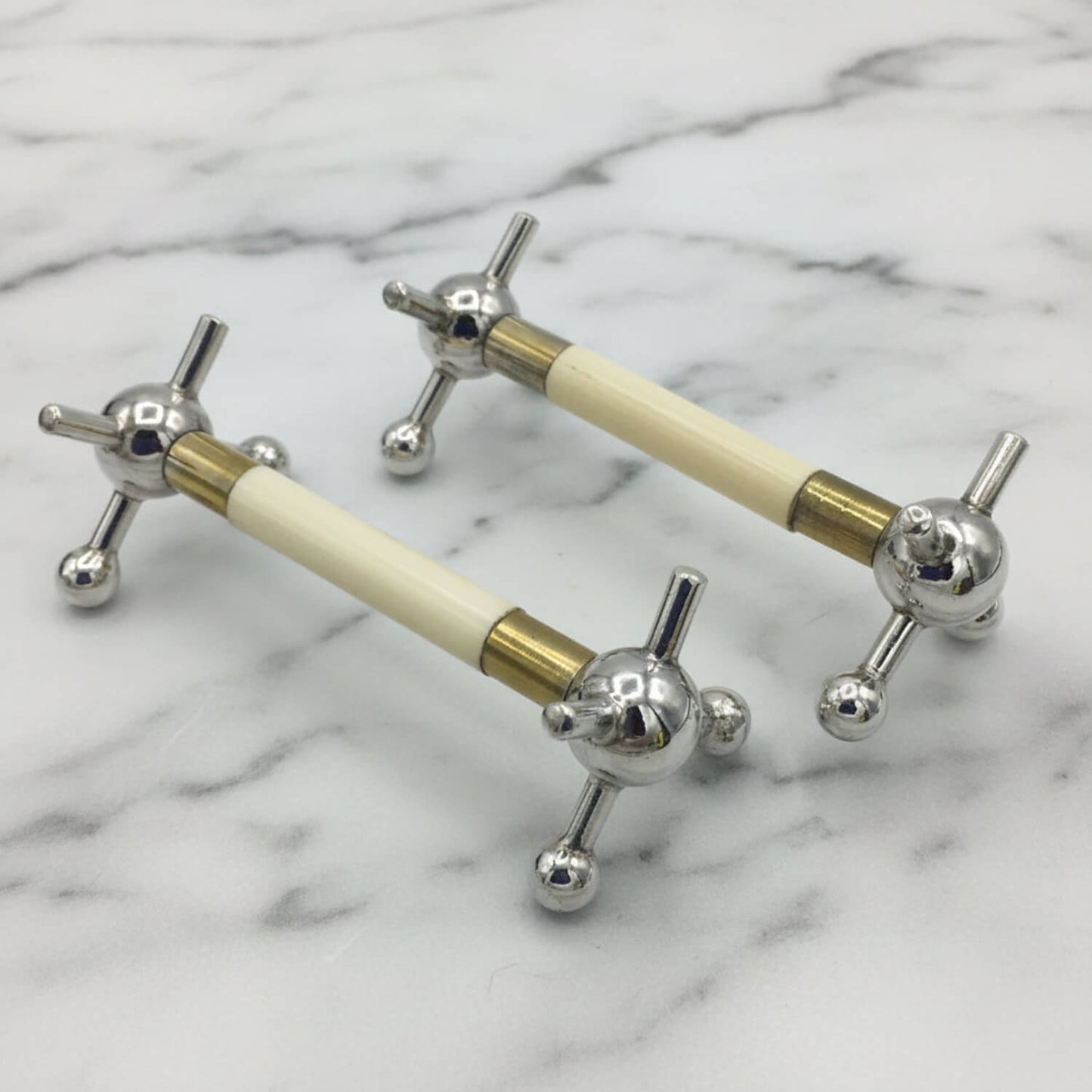 Pair of Antique Silver Plated Knife Rests on a marble surface