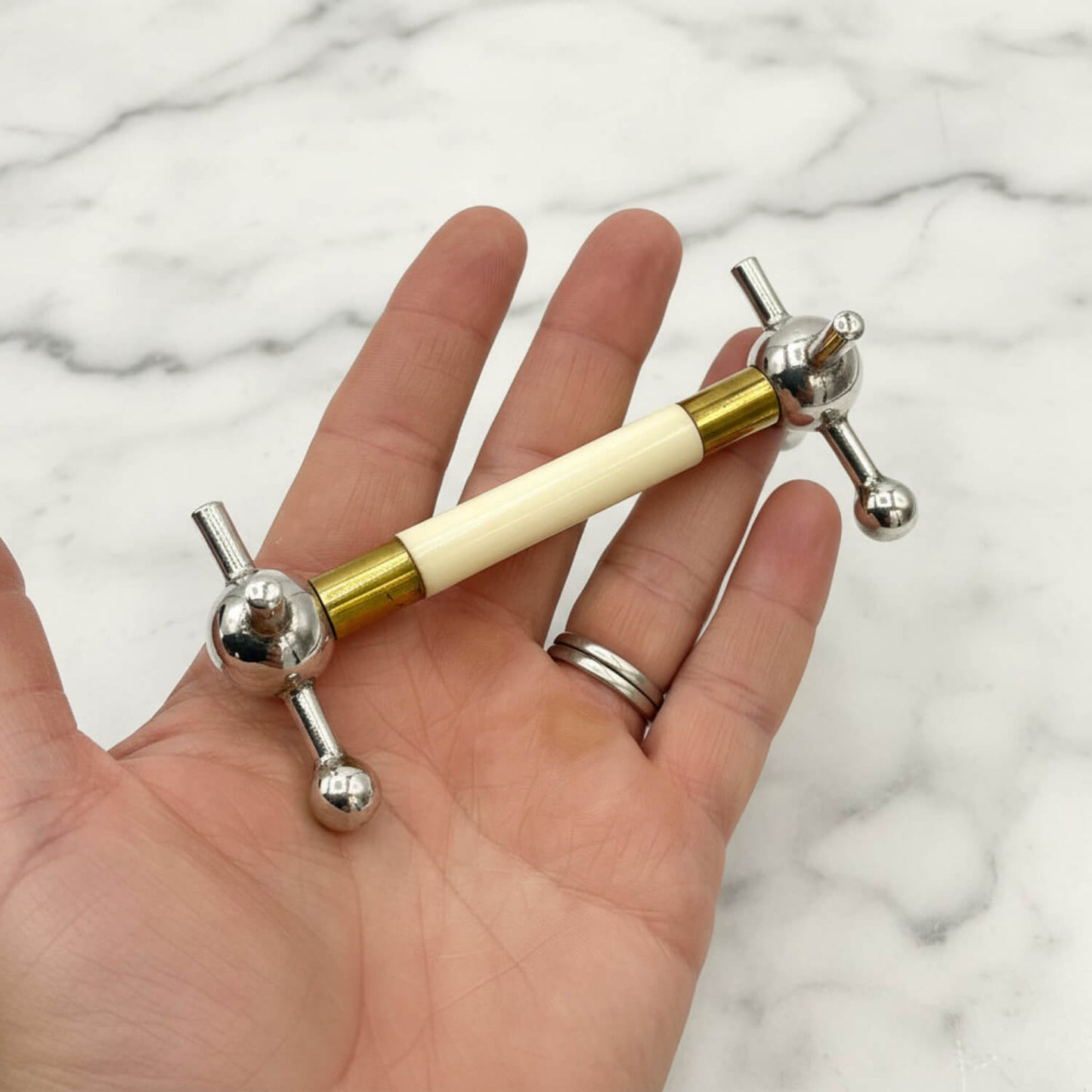 Antique Silver Plated Knife Rest held in a hand with a marble surface