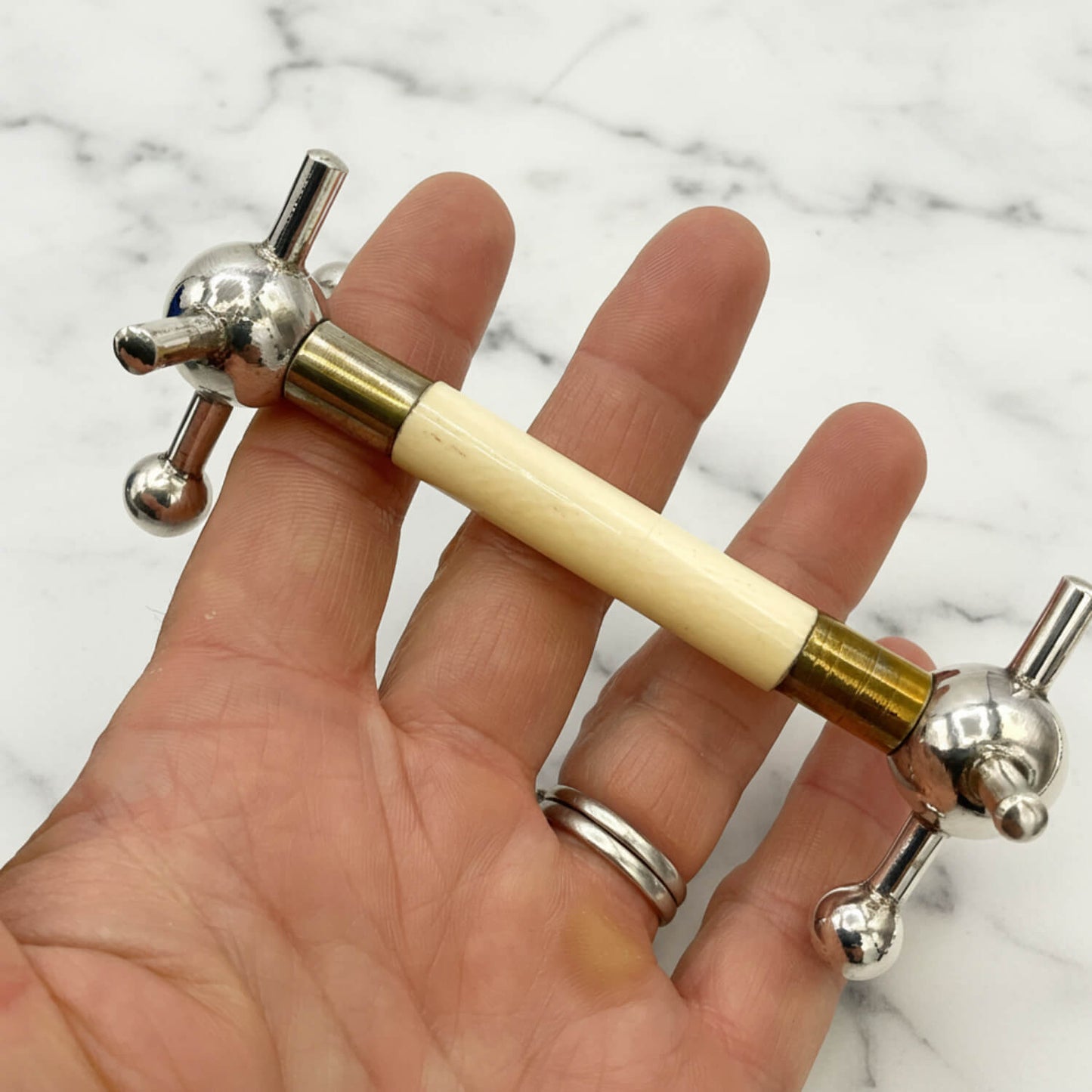 Antique Silver Plated Knife Rest held in a hand with a marble surface