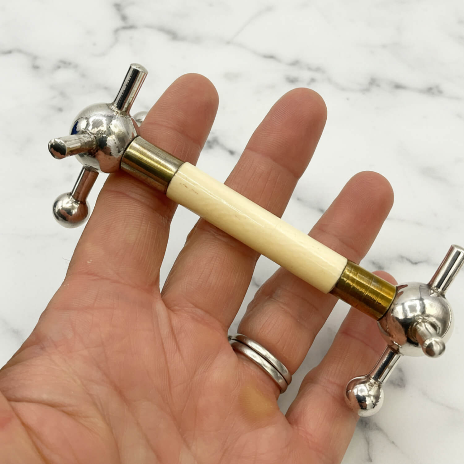 Antique Silver Plated Knife Rest held in a hand with a marble surface