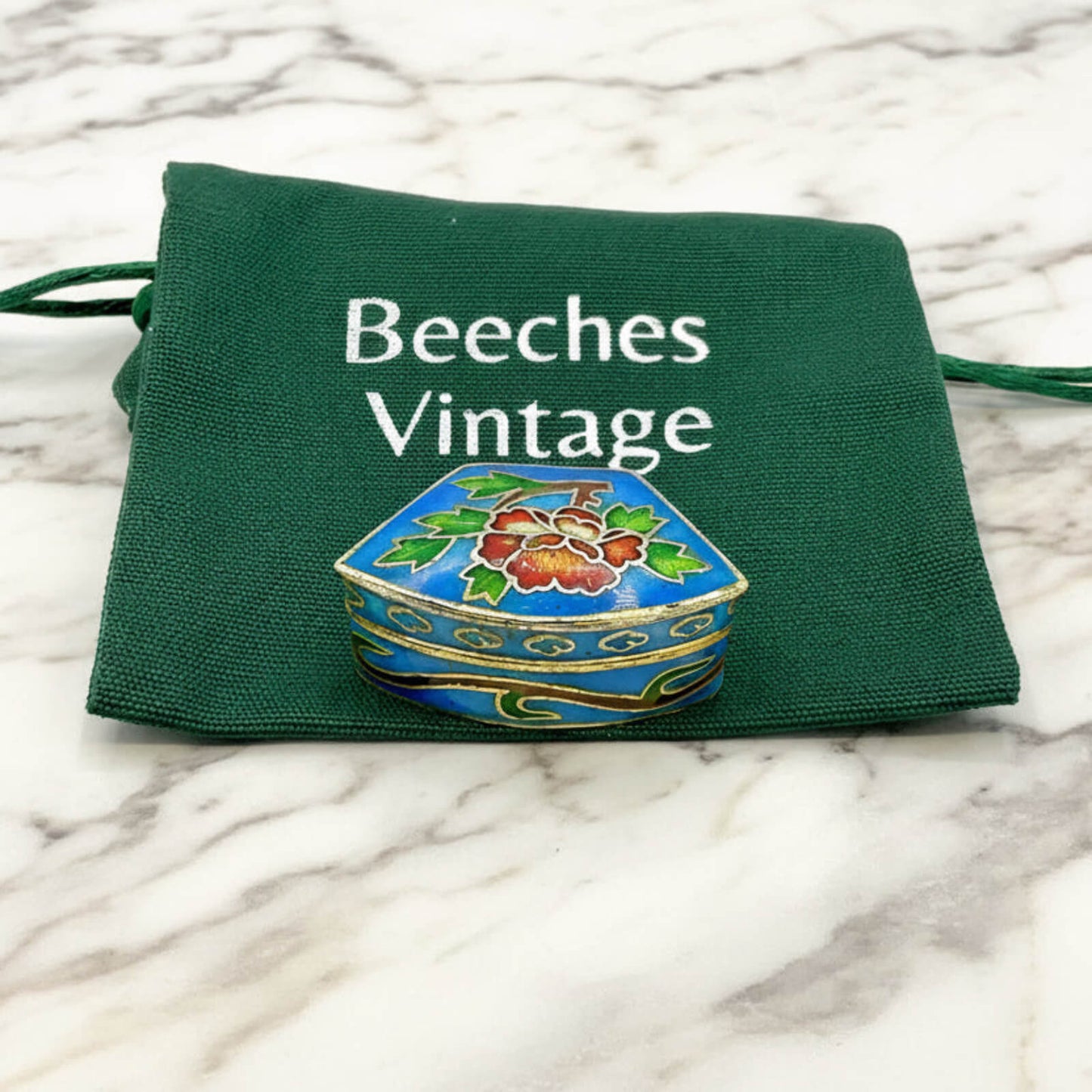 Chinese Cloisonné Enamel Pill Box on a green gift bag and marble surface