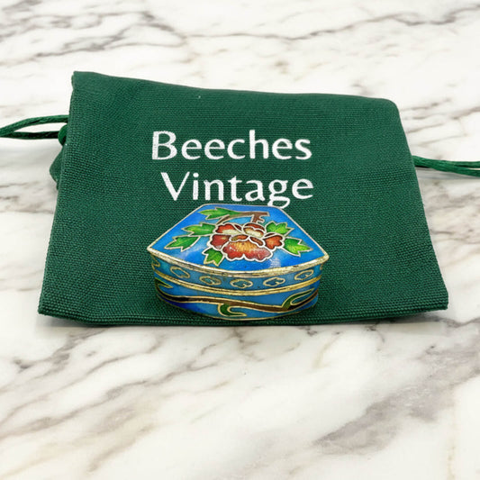 Chinese Cloisonné Enamel Pill Box on a green gift bag and marble surface
