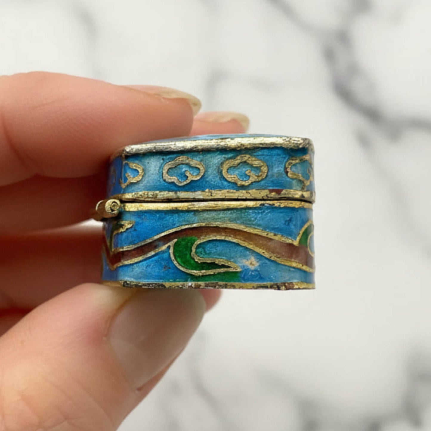 Chinese Cloisonné Enamel Pill Box held in fingers showing a side view