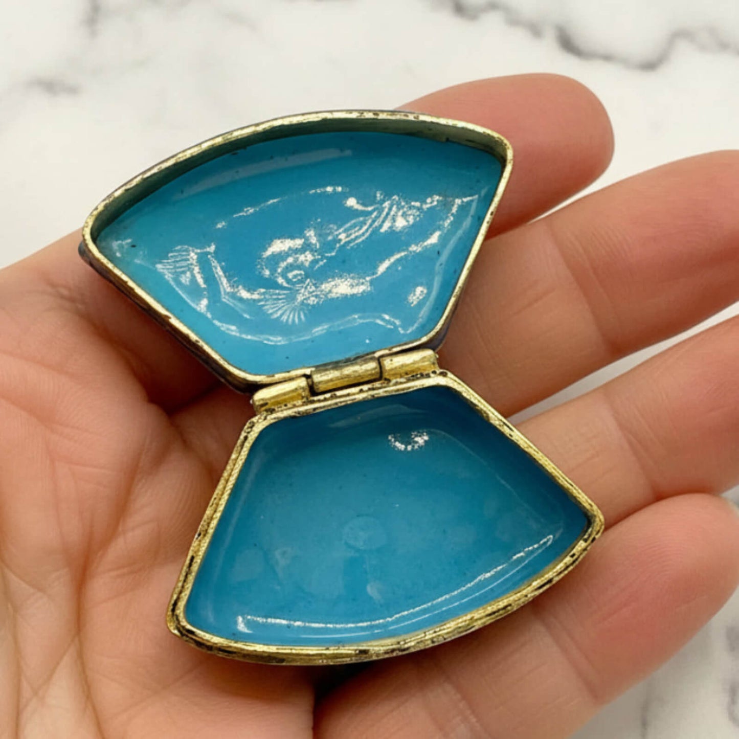 Chinese Cloisonné Enamel Pill Box inside showing blue enamel held in a hand with a marble background