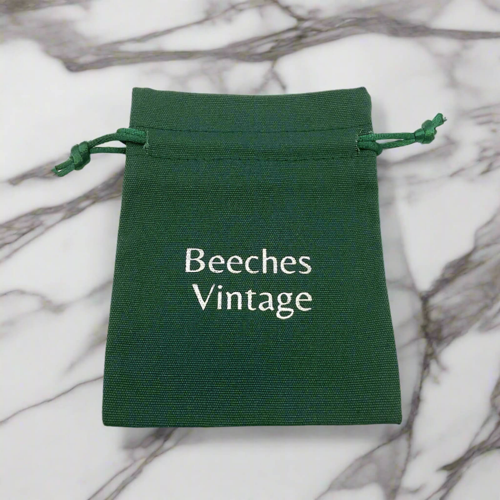 Green drawstring pouch with 'Beeches Vintage' text on a marble background