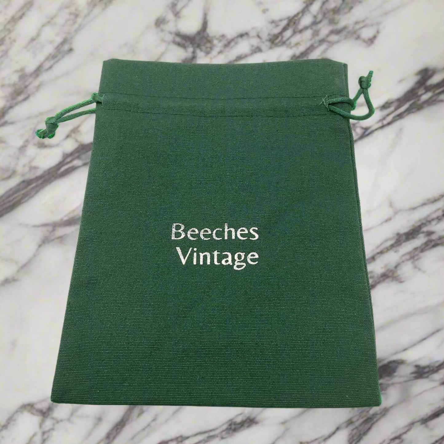 Green drawstring pouch with 'Beeches Vintage' text on a marble background