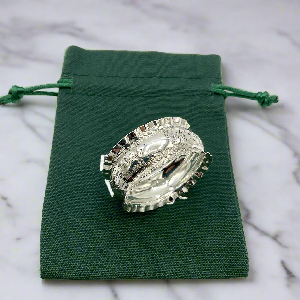 Silver napkin ring on a green bag on a marble worktop