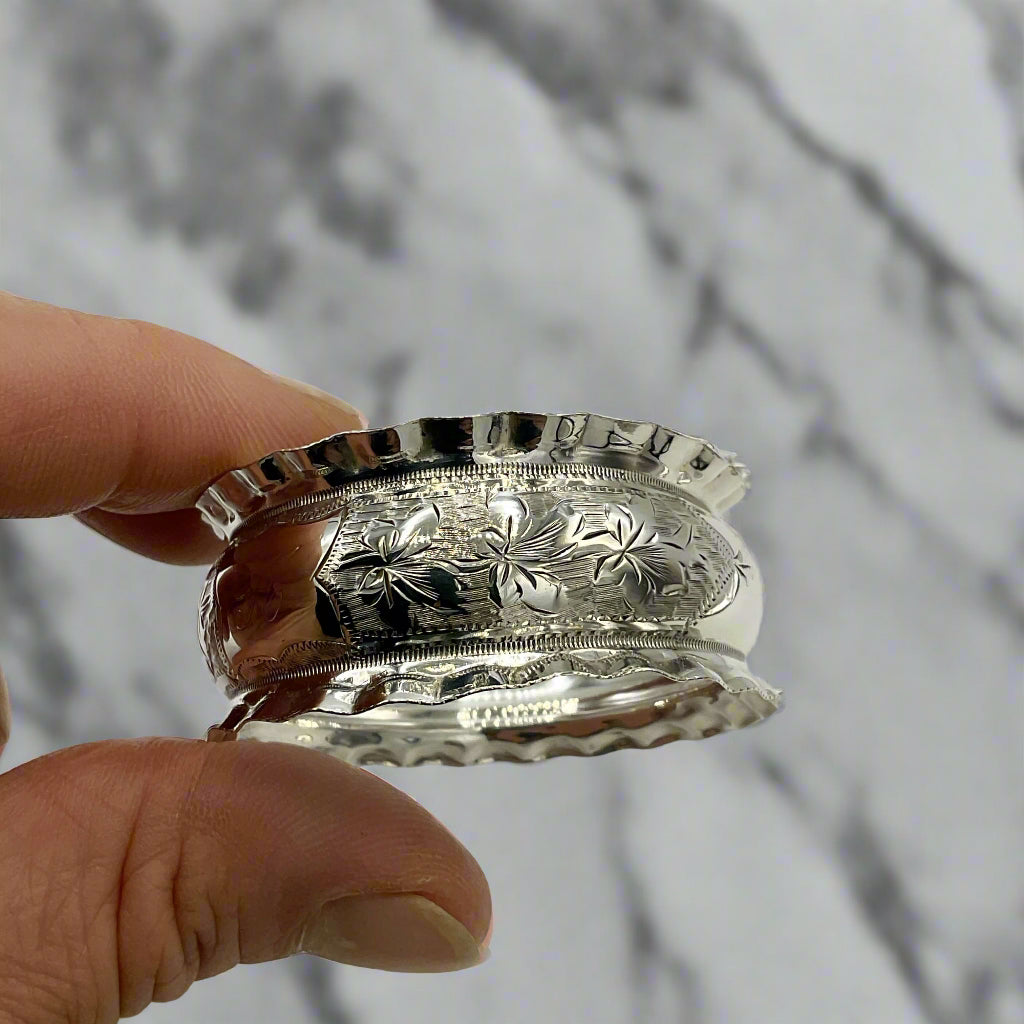Silver napkin ring held between two fingers against a marble background